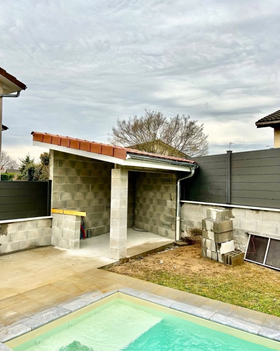 Abri de jardin en moellons et terrasse au bord d'une piscine
